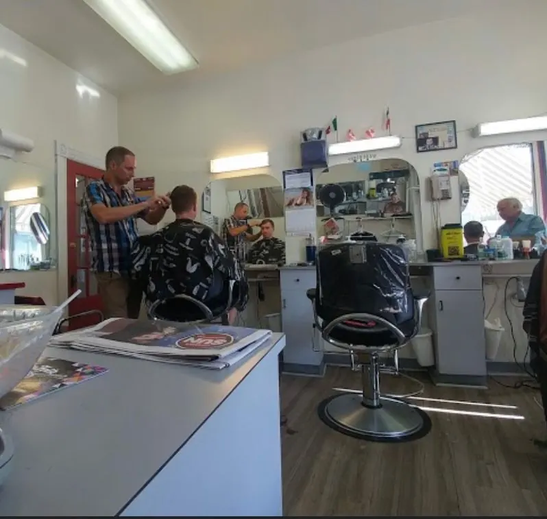 Inside Ernesto's Barber Shop: barbers at work beside chairs, mirrors and shelves of supplies